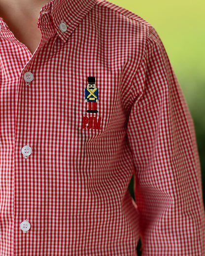 Red and white checkered shirt with a embroidered design on a blurred green background