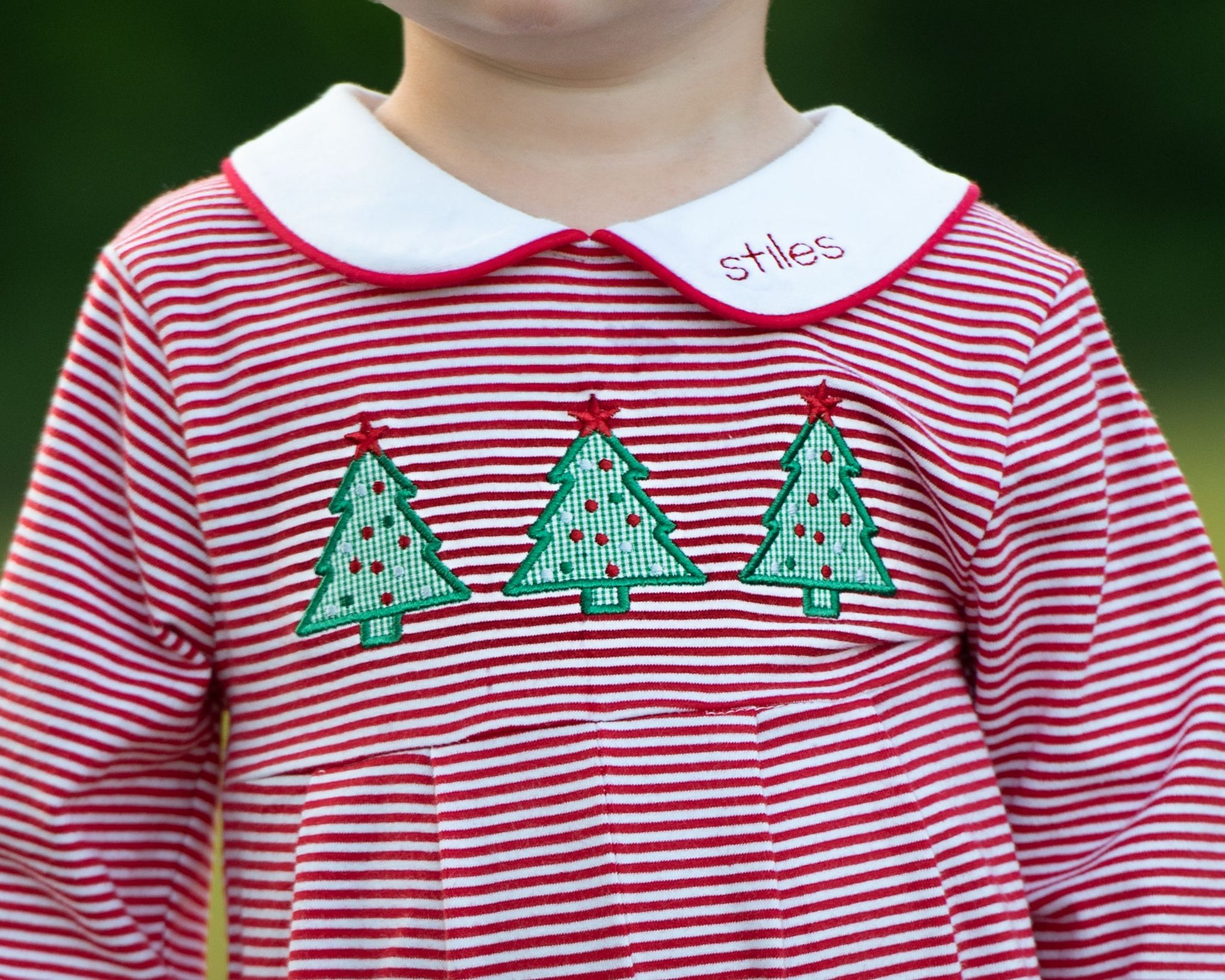 Red and white striped shirt with green Christmas tree designs and 'stiles' on a blurred background
