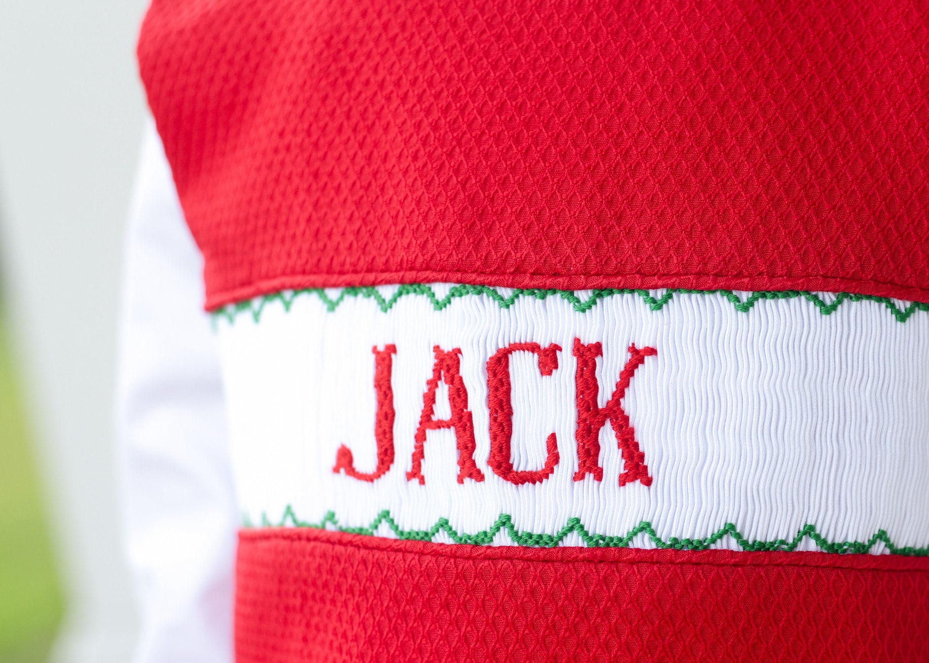 Red and white sweater with 'JACK' embroidered on it against a blurred background