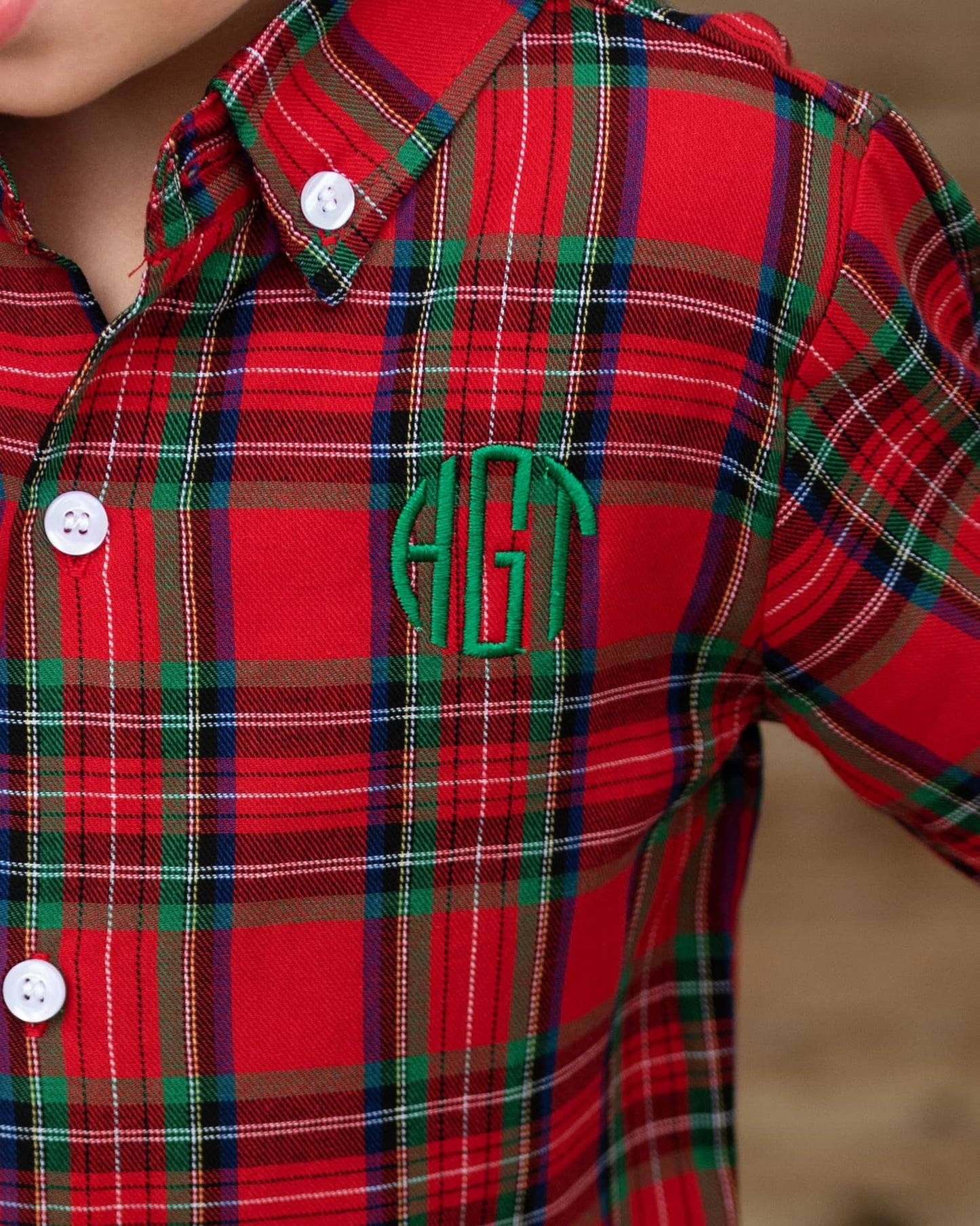 Red plaid shirt with a green monogram on a blurred background