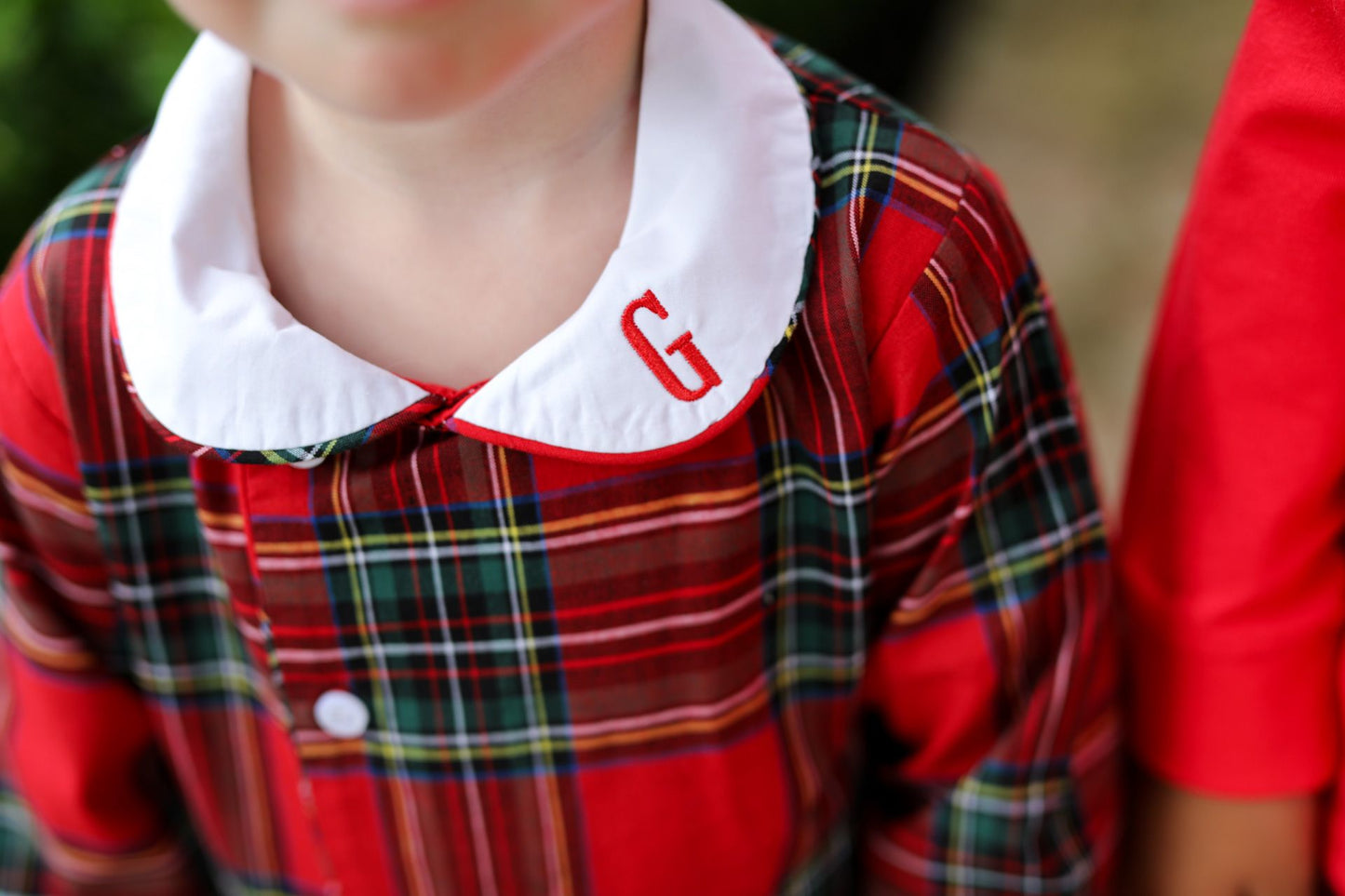 Red plaid shirt with white collar and red letter 'G' worn by a child