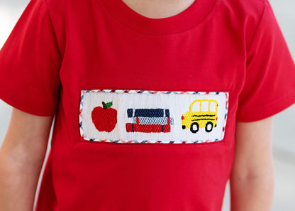 Red t-shirt with a pocket featuring an apple, car, and school bus design.