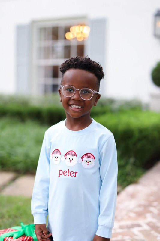 Young boy wearing a blue shirt with santa appliques on it 