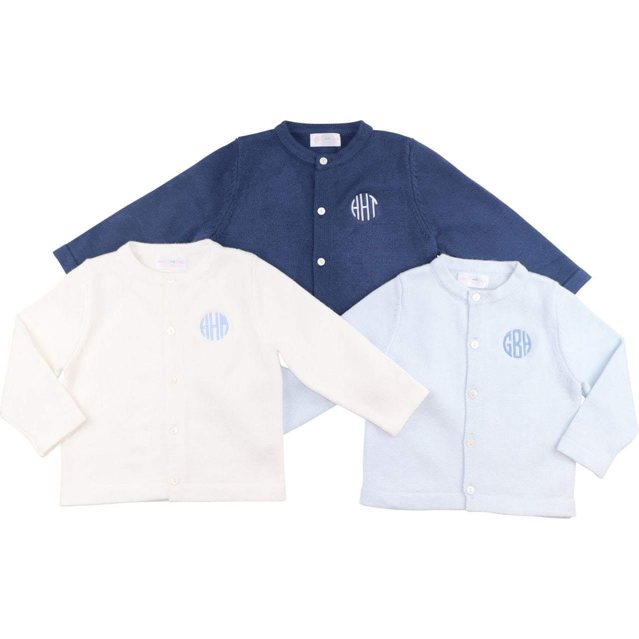 Three button-up shirts in blue, white, and light blue with monogrammed logos on a white background.