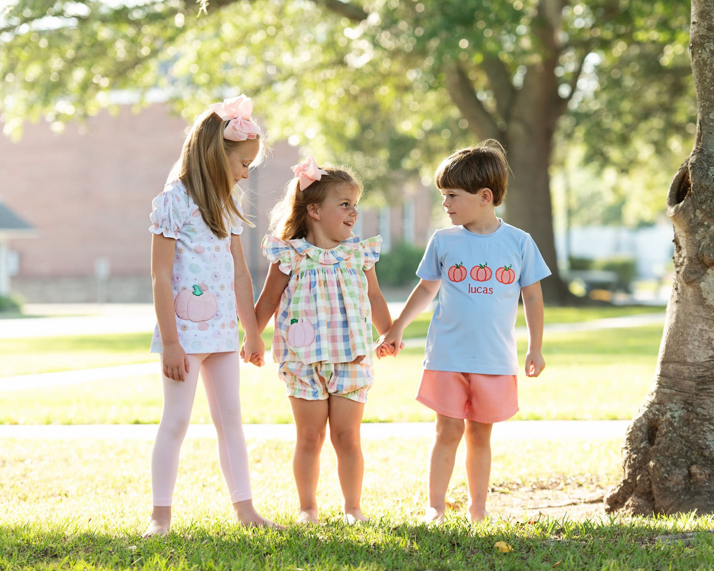 Three children holding hands in a park setting 