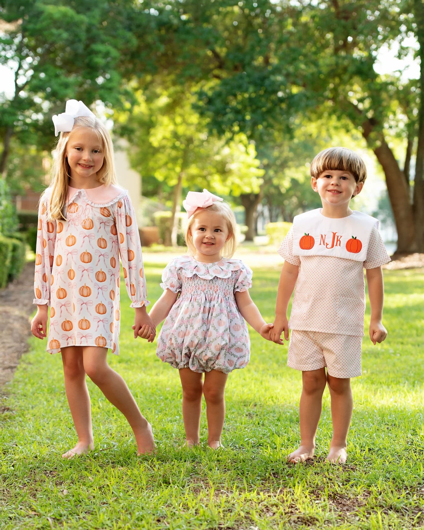 Three_children_holding_hands_in_a_park_wearing_matching_outfits.