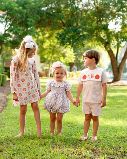 Three children holding hands in a park with greenery in the background