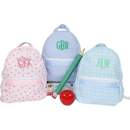 Three colorful backpacks with monograms, a red apple, and green pencil on a white background