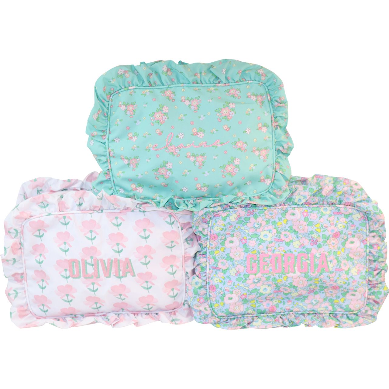 Three floral-patterned zip pouches with monogramming on a white background