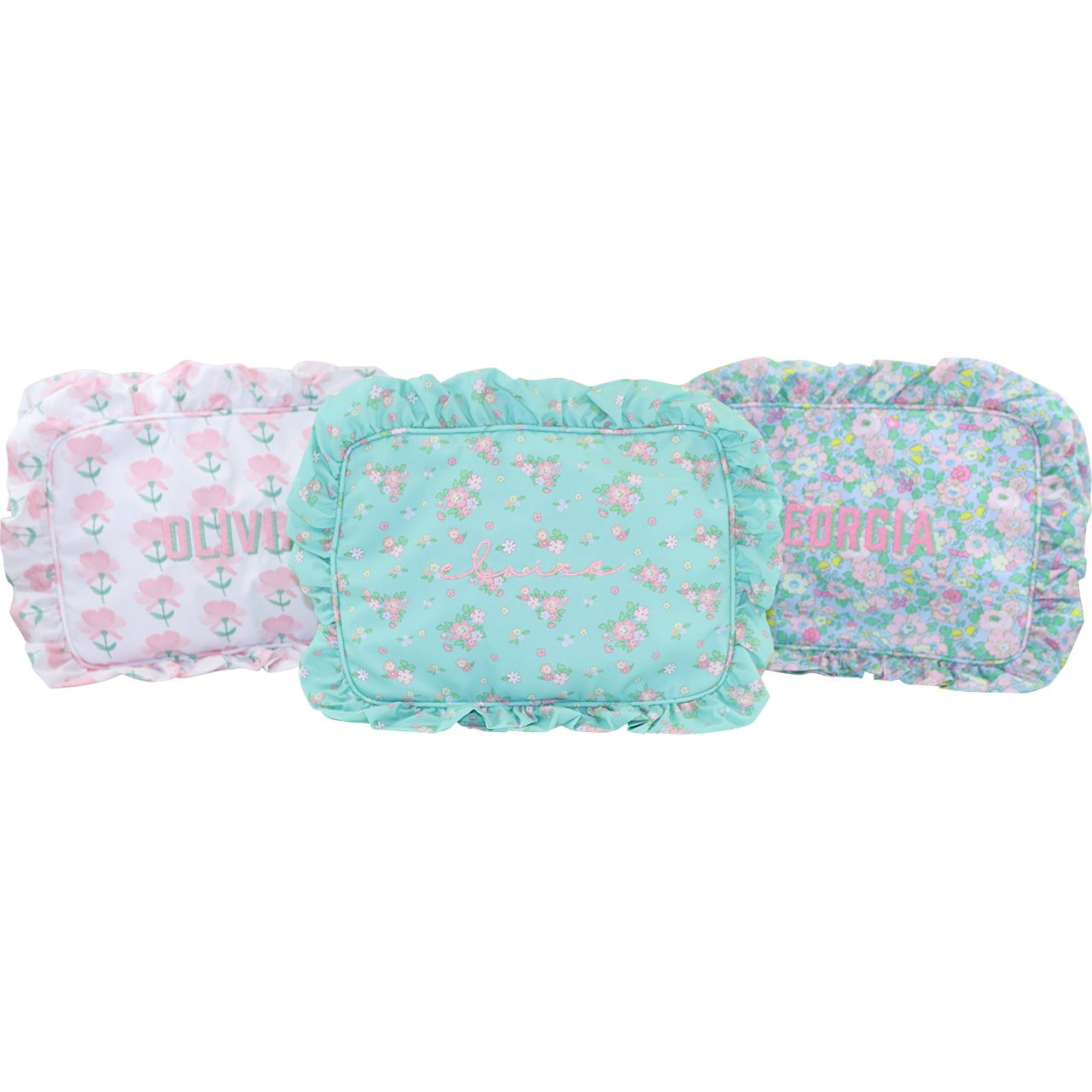 Three floral-patterned zip pouches with monogramming on a white background