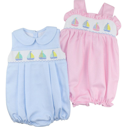 Two baby rompers, one blue and one pink, with sailboat embroidery on a white background.