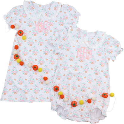 Two baby rompers with floral patterns and colorful pom-poms on a white background

