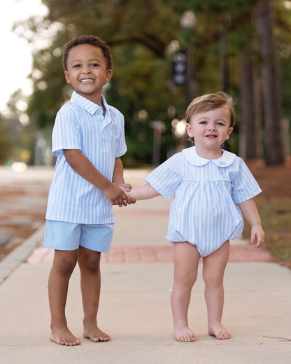 Two boys standing outside wearing matching blue striped outfits