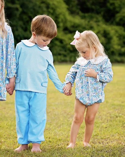 Two children holding hands in a grassy outdoor setting