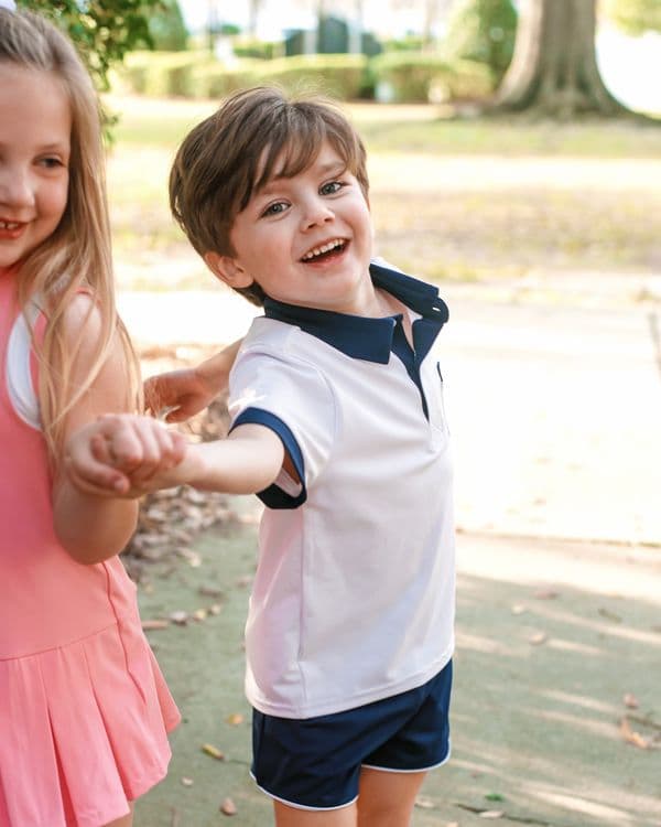 Two children holding hands outdoors with a blurred natural background