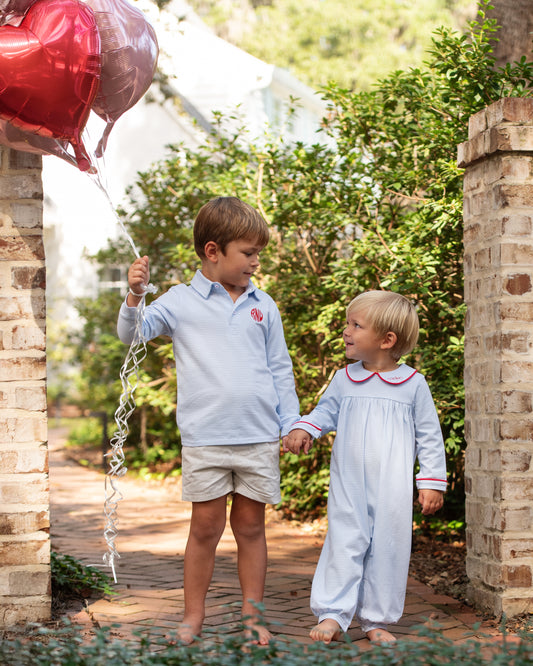 Two children holding hands outdoors with a heart-shaped balloon.