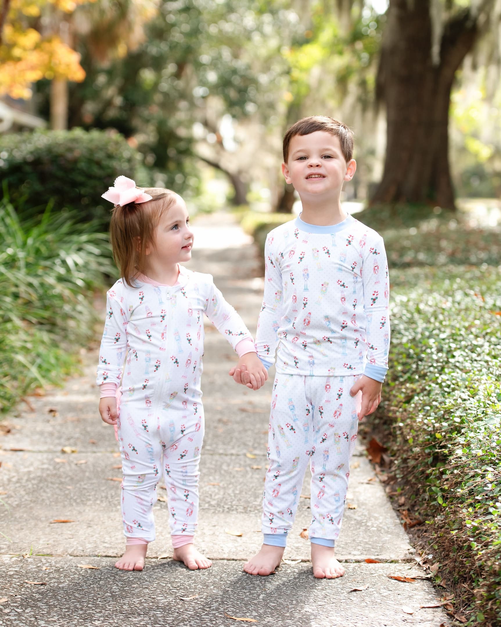 Two children in matching pajamas standing on a path outdoors.