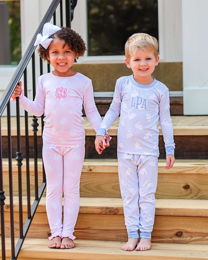 Two children in matching pajamas standing on wooden steps.