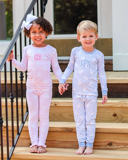 Two children in matching pajamas standing on wooden steps.