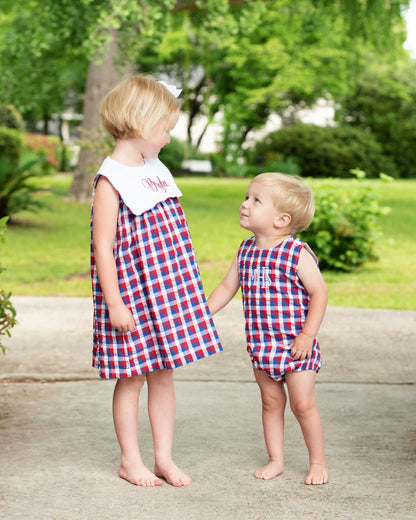 Two children in matching red, white, and blue outfits standing outdoors on a path.