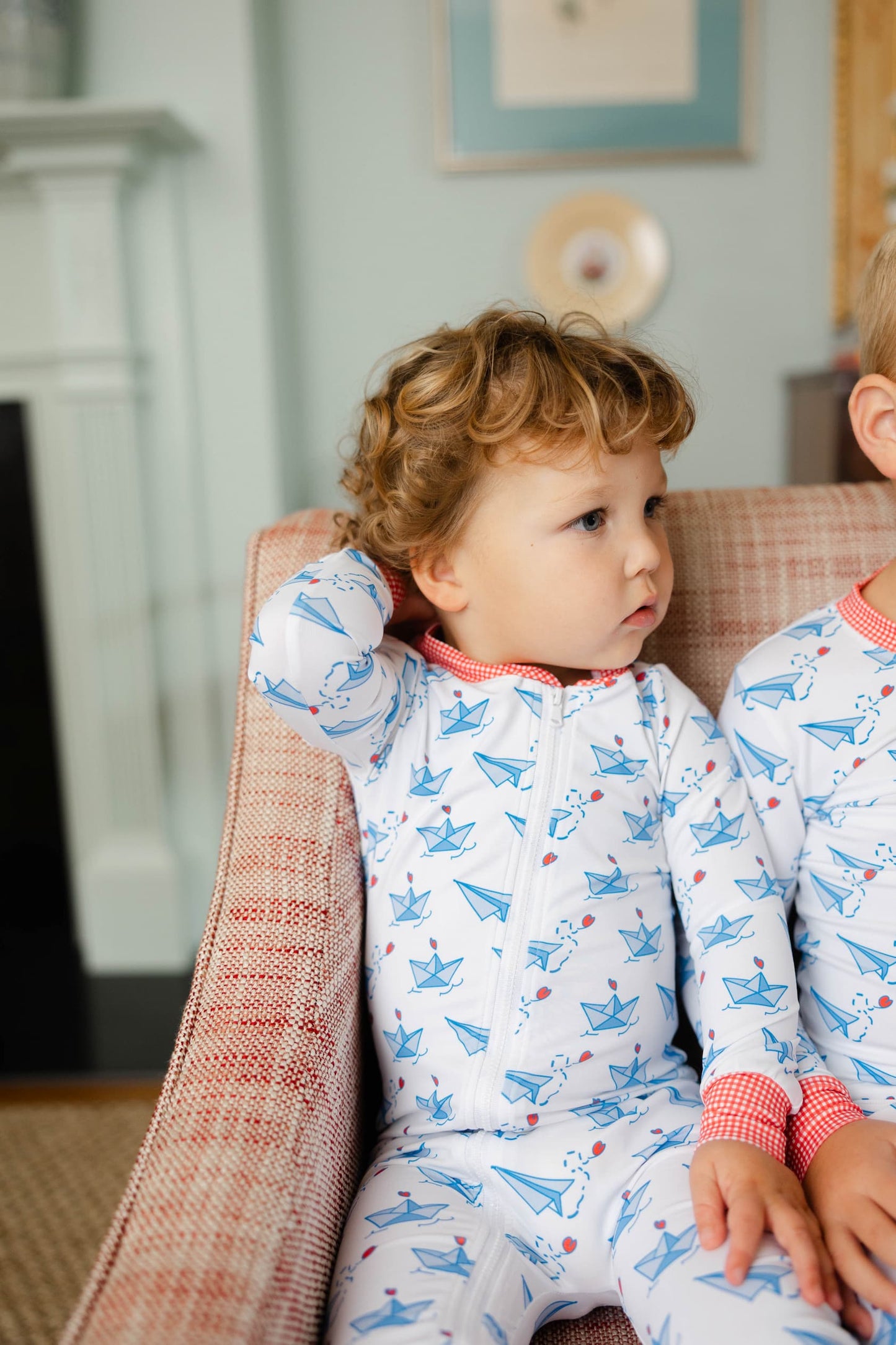 Two children in pajamas sitting on a couch in a cozy room.