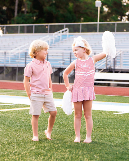 Two children on a grassy field with bleachers in the background