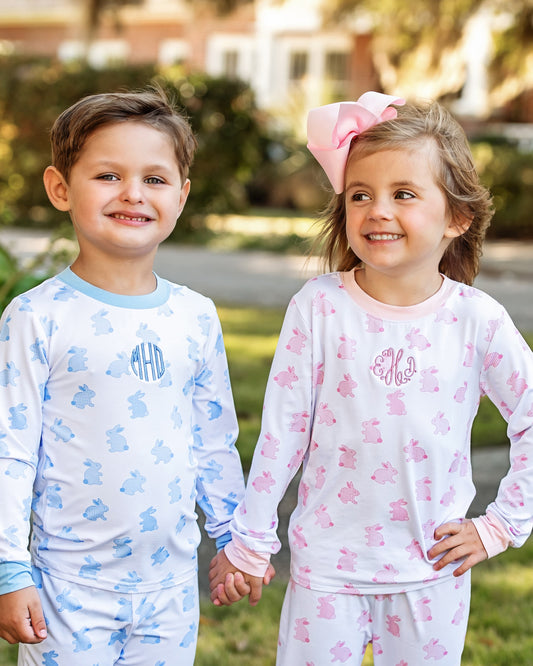 Two children wearing bunny pajamas with monograms, standing outdoors.