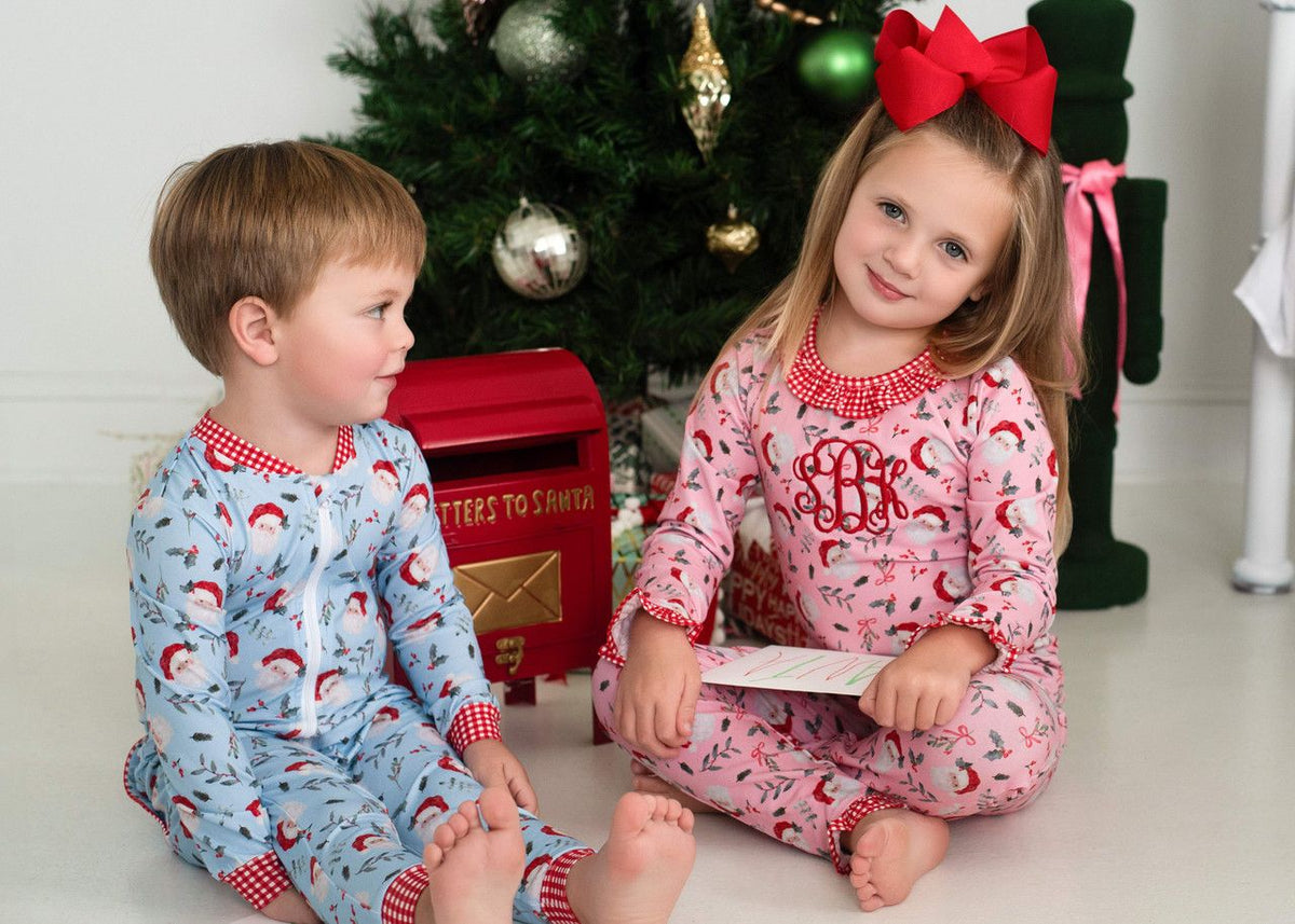 Two children wearing matching Santa pajamas sitting together