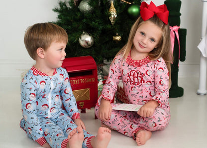 Two children wearing matching Santa pajamas sitting together
