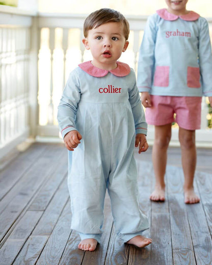 Two children wearing matching outfits with visible names on a wooden floor.