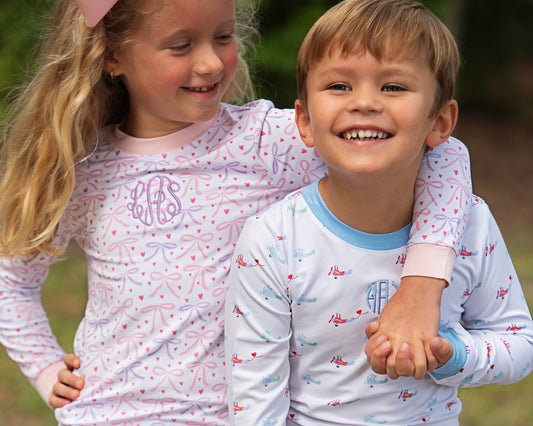 Two children wearing matching pajamas with a monograms outdoors.