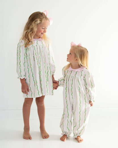 Two children wearing matching pajamas with green wavy patterns on a white background