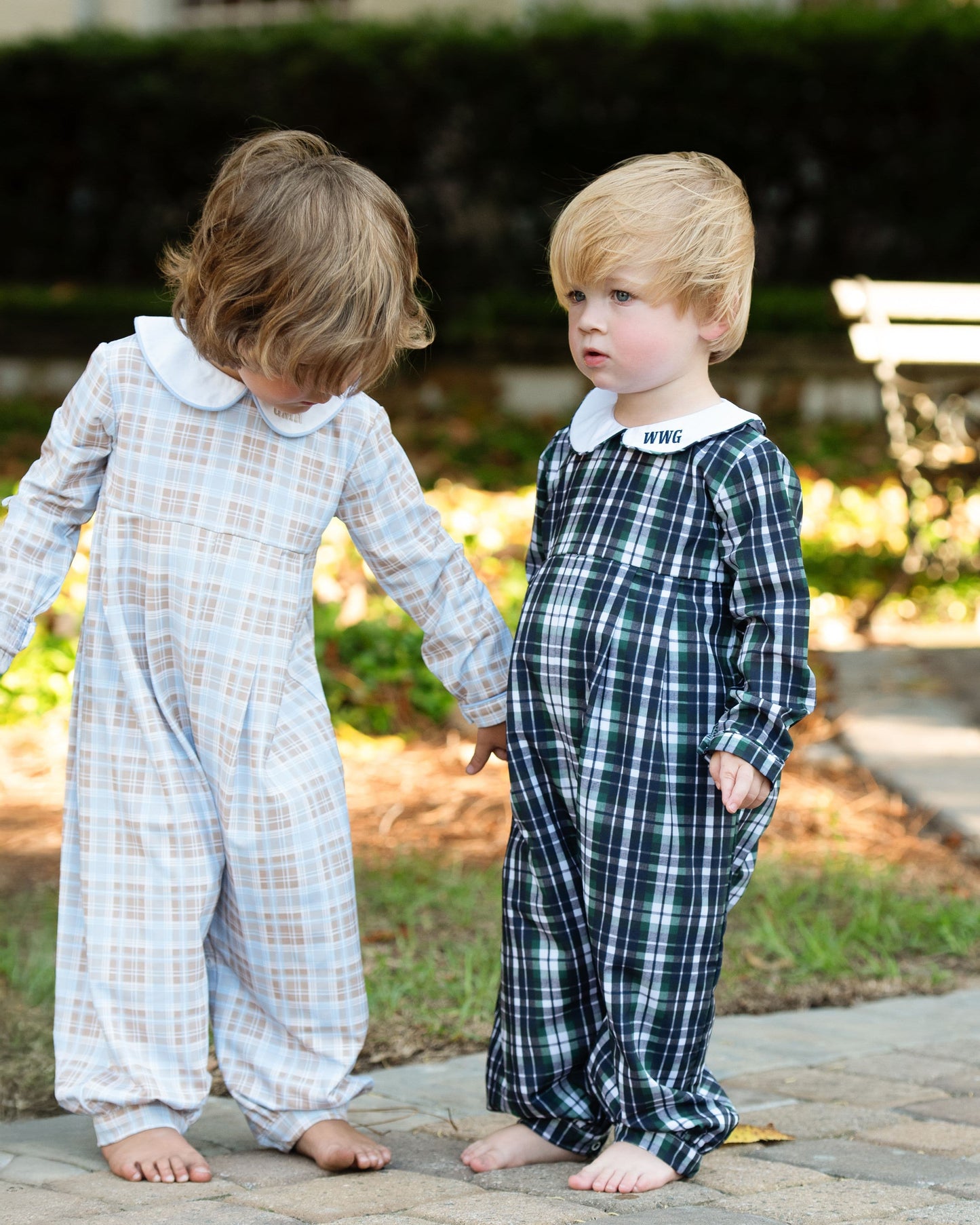 Two children wearing plaid pajamas standing on a sidewalk.