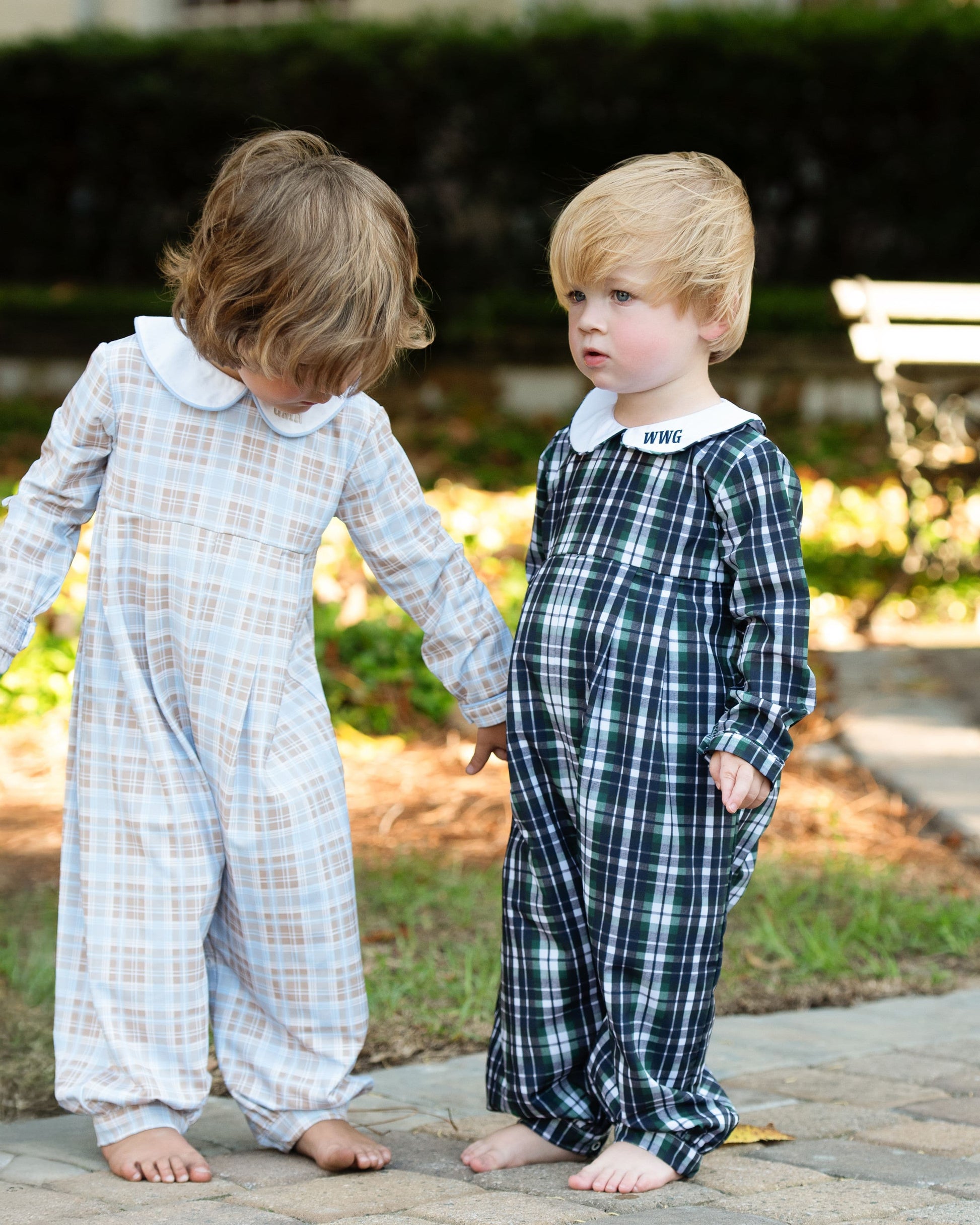 Two children wearing plaid pajamas standing on a sidewalk.