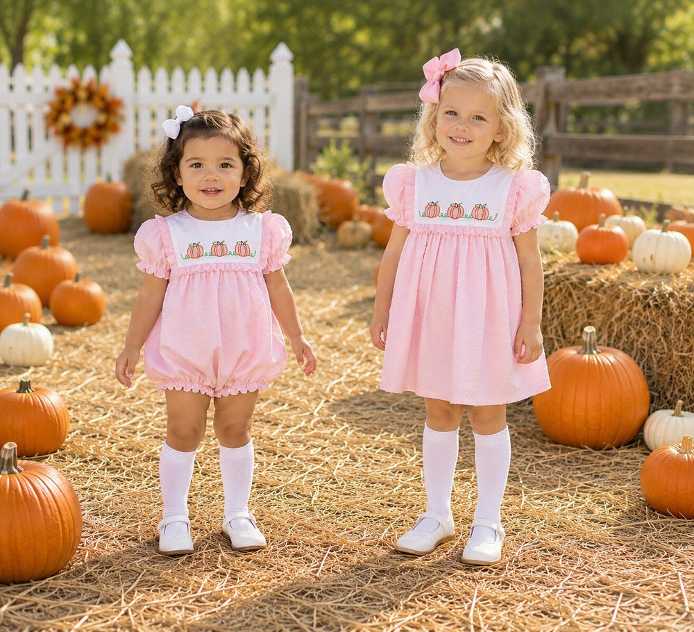 Two girls wearing matching pink pumpkin outfits that work for fall and Thanksgiving