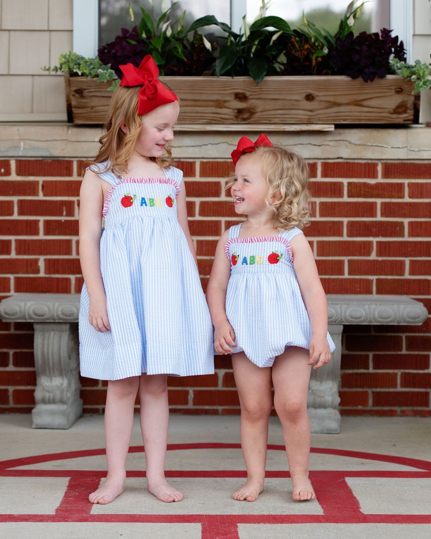 Two little girls wearing matching seersucker back to school outfits