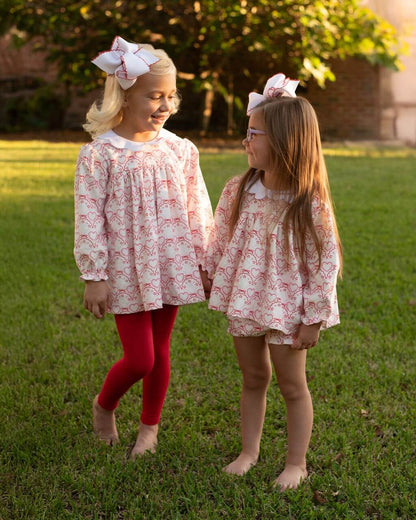 Two young girls in matching dresses standing on grass