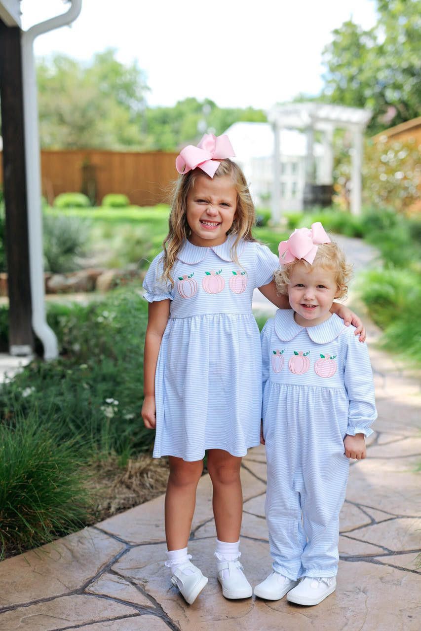 Two young girls in matching light blue outfits with pink accents standing outdoors on a stone path 2