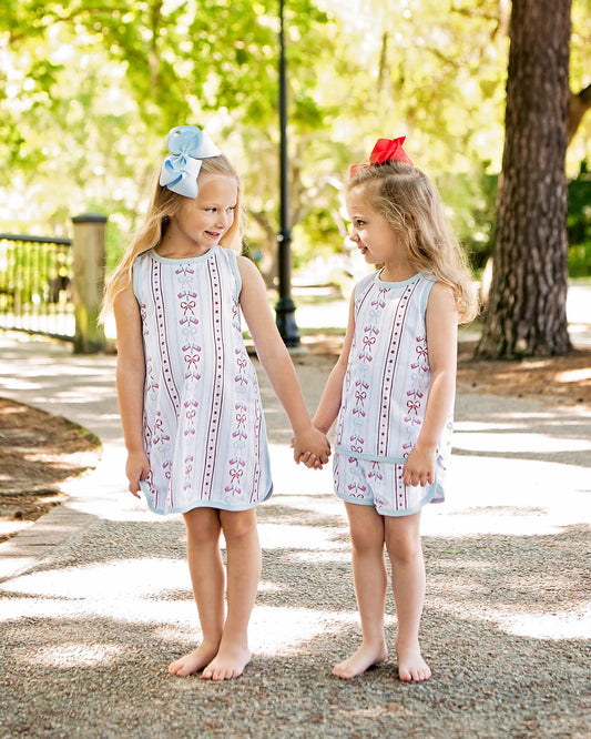 Two young girls in matching outfits holding hands outdoors.