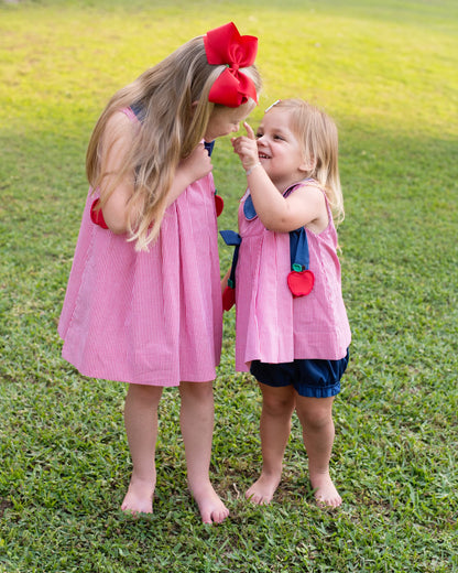 Two young girls in matching outfits standing on the grass.