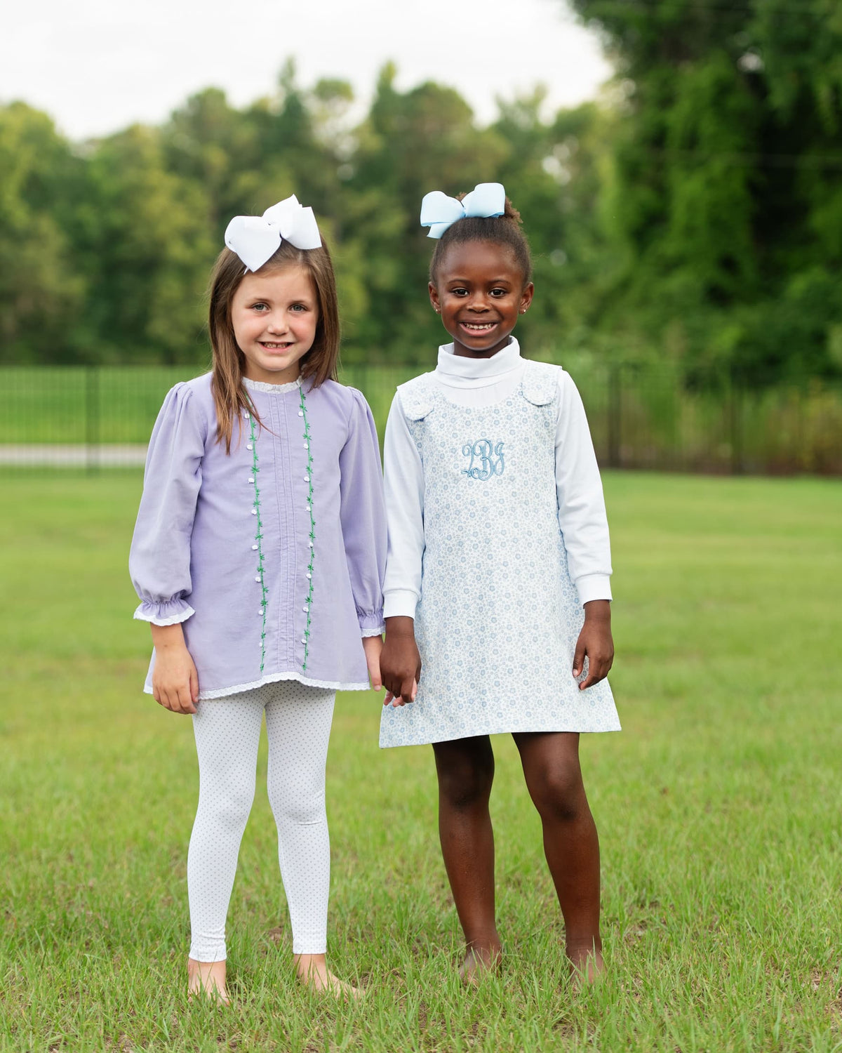 Two young girls standing on grass wearing fall outfits