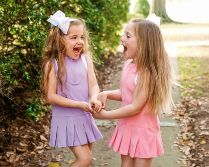 Two young girls wearing athletic dresses outside. 