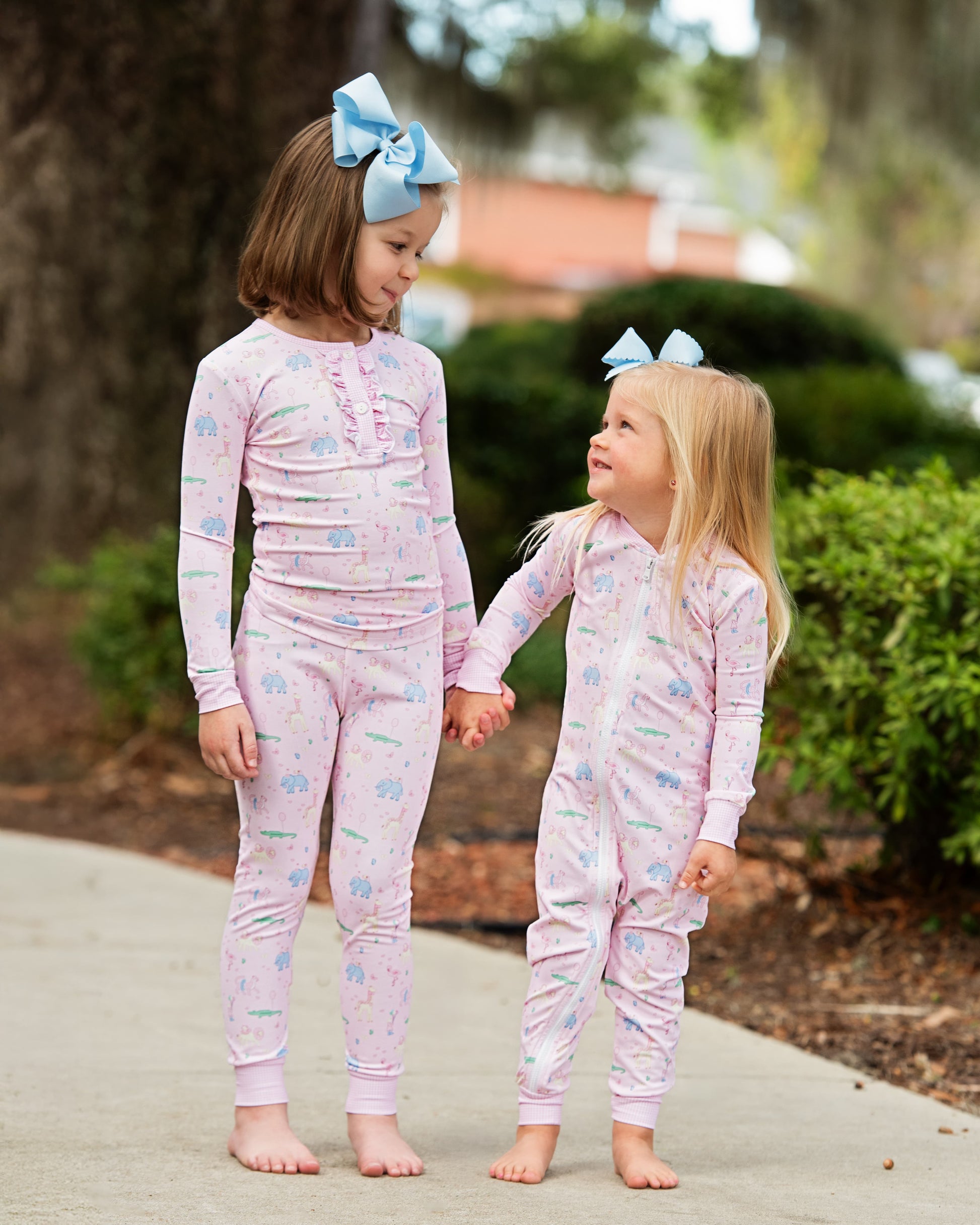 Two young girls wearing matching birthday pajamas with a garden background