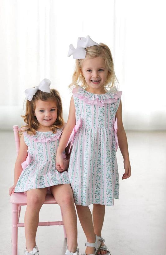 Two young girls wearing matching outfits with bows in their hair on a white background