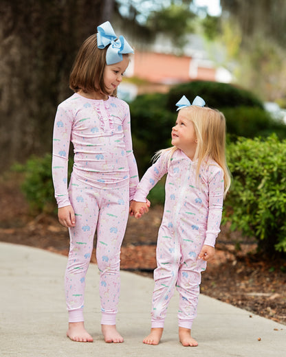 Two young girls wearing matching pajamas with a garden background