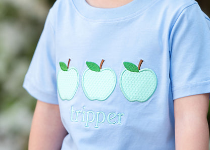 Up close image of a blue shirt and three appliqued apples
