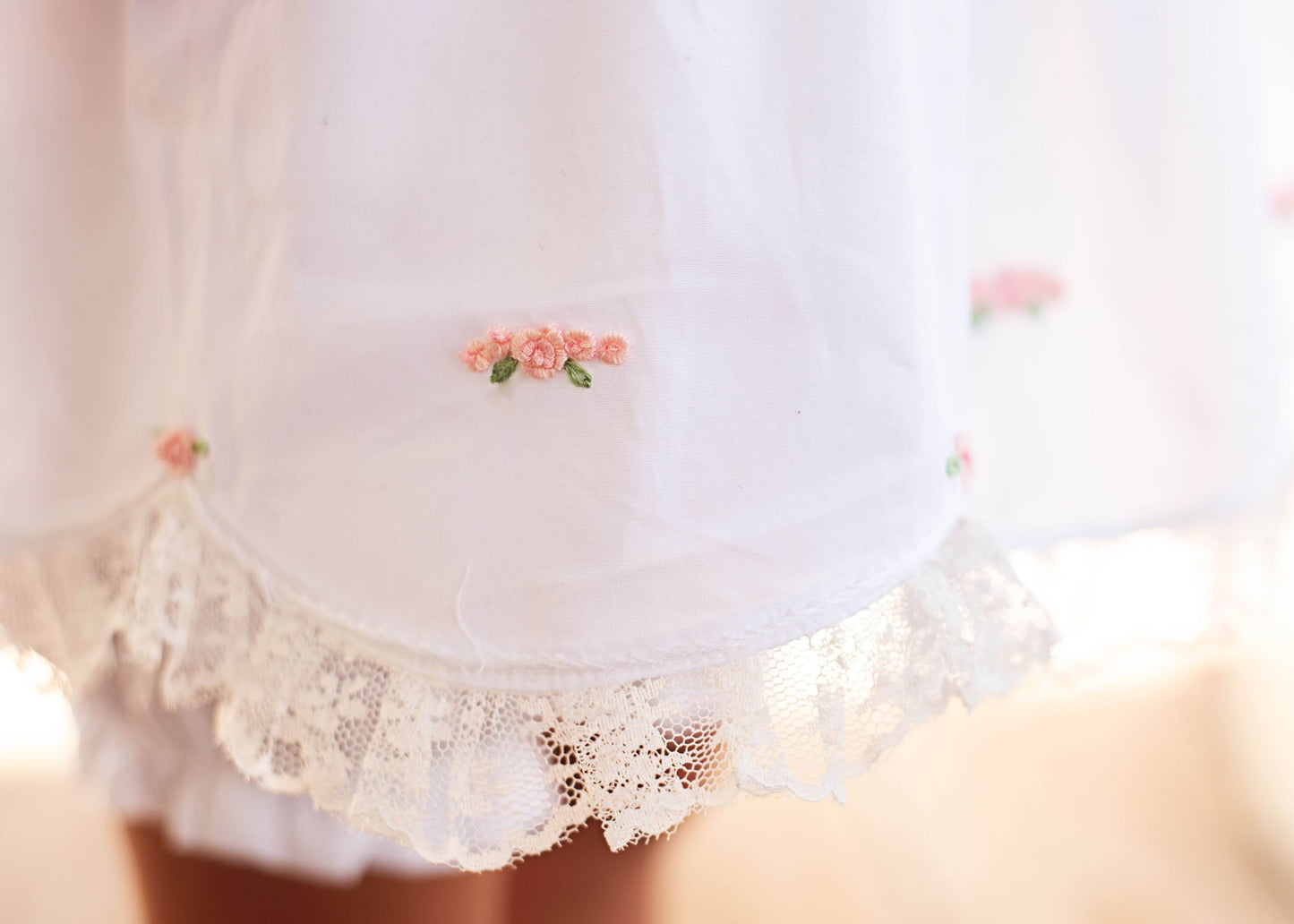 White lace-trimmed garment with floral embroidery on a blurred background