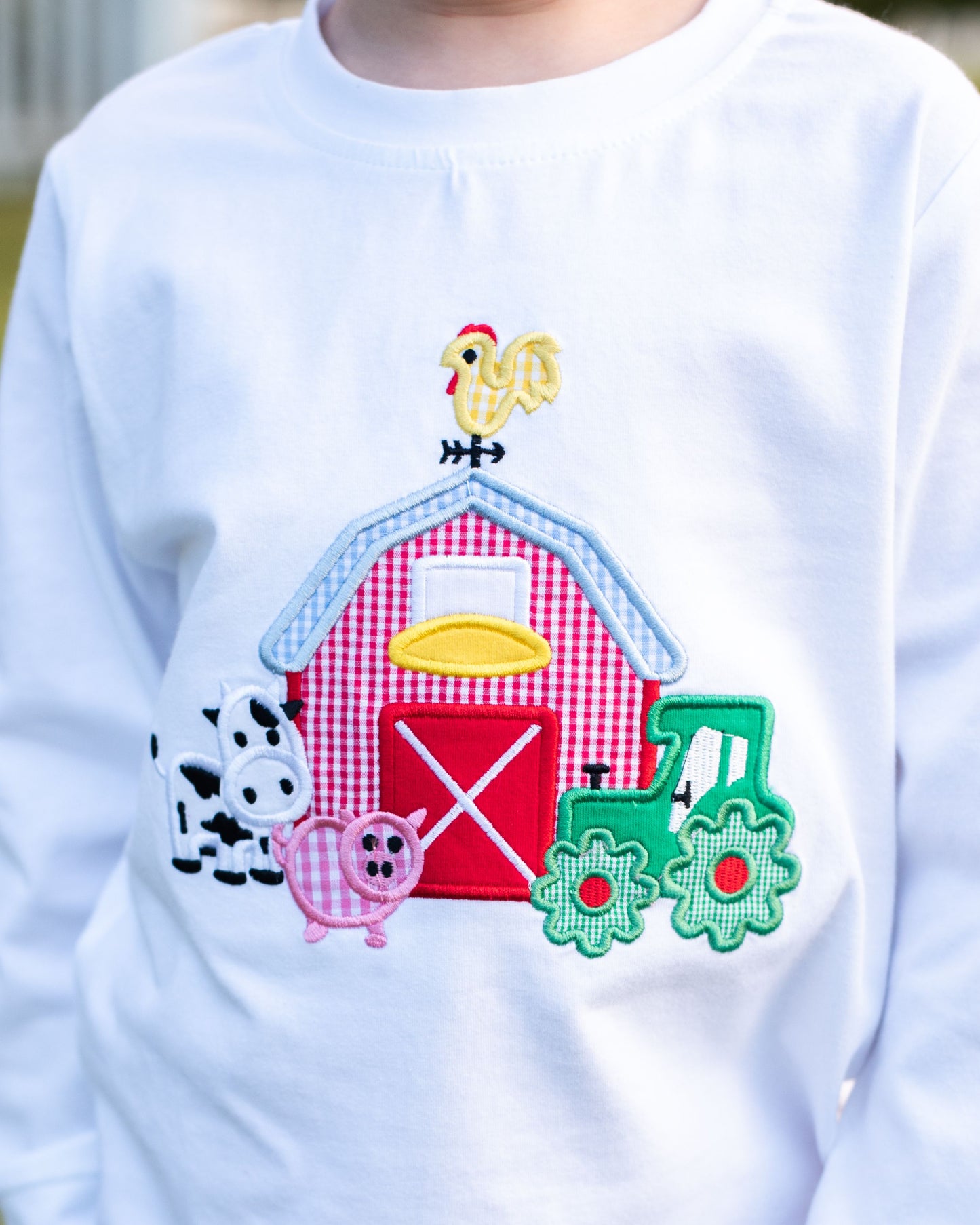 White sweatshirt with farm-themed appliqué including a barn, animals, and a train.
