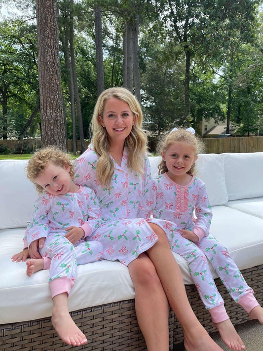 Woman and two children in matching pajamas sitting on a couch outdoors.