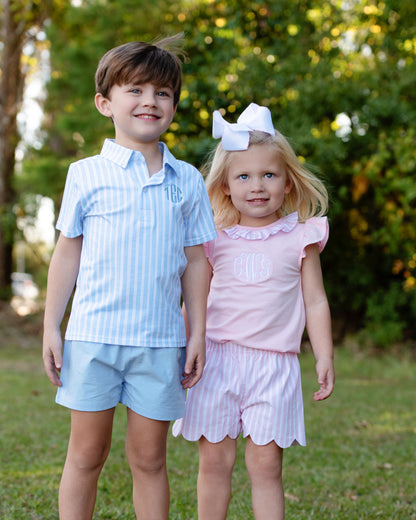 Young boy and girl standing outside wearing matching blue and pink striped outfits